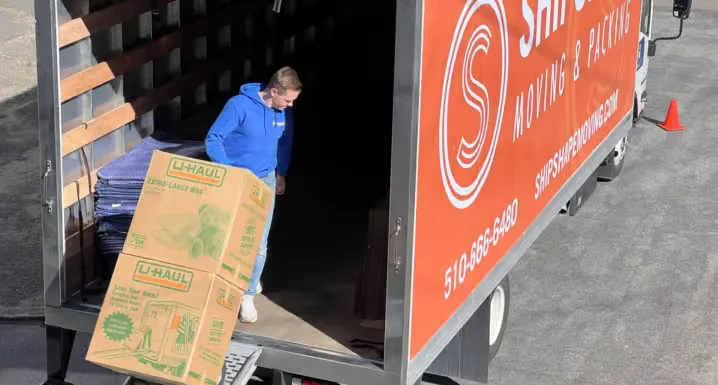 Movers carrying wrapped boxes through an apartment building hallway