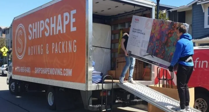 Residential movers loading furniture into a ShipShape Moving truck