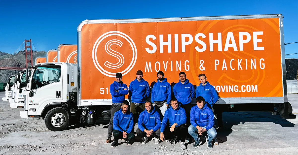 ShipShape Moving crew in front of a row of ShipShape Moving & Packing trucks near the Golden Gate Bridge